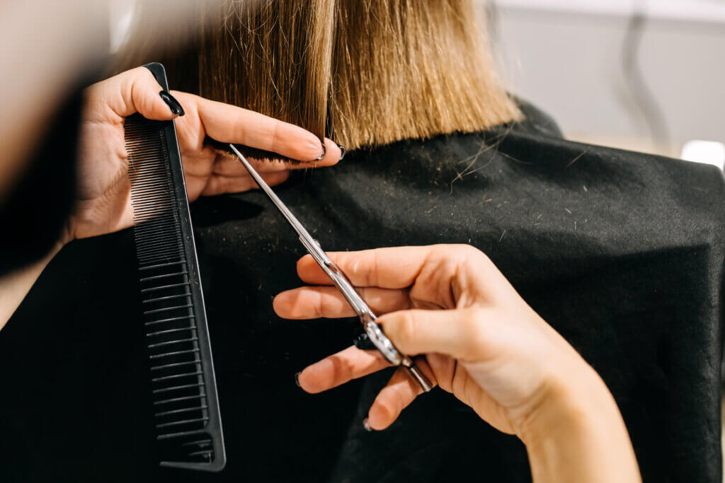 Process of hair cutting at a beauty salon, using scissors. Hair